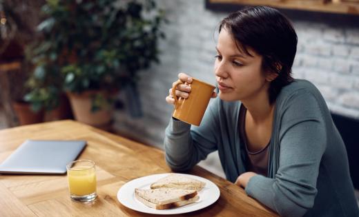 kobieta jedząca posiłek, obok stoi filiżanka z kawą